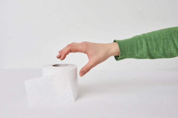 Femme tient un rouleau de tissu en mains sur un mur blanc.