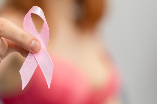 Photo une femme tient un ruban rose dans sa main, symbole de la lutte contre le cancer du sein.