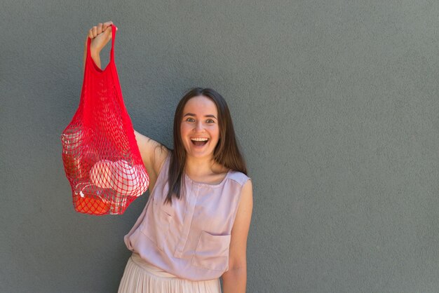 La femme tient un sac en filet avec des produits