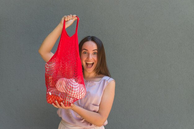 La femme tient un sac en filet avec des produits