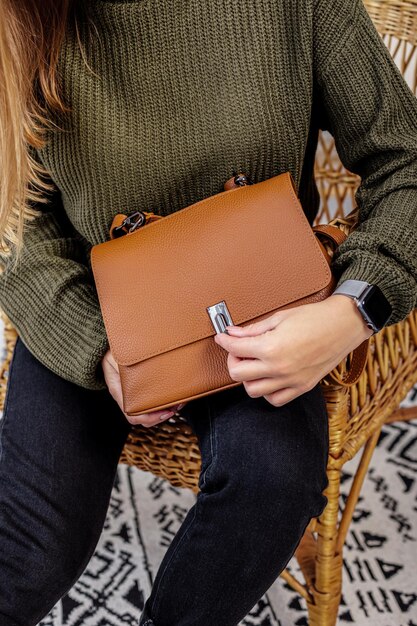 Une femme tient un sac à main à la mode en cuir marron dans ses mains. Nouvelle collection de sacs à main pour femme