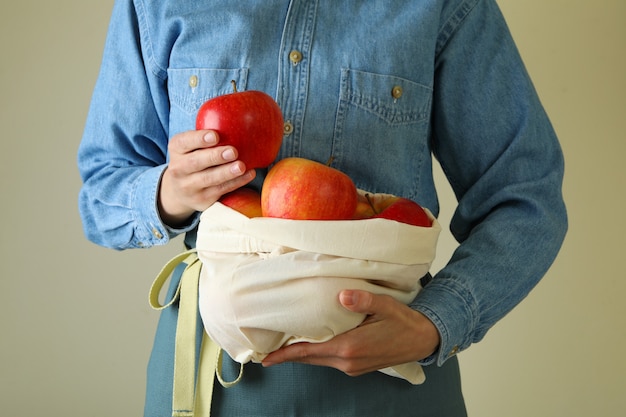 La femme tient le sac avec les pommes rouges mûres