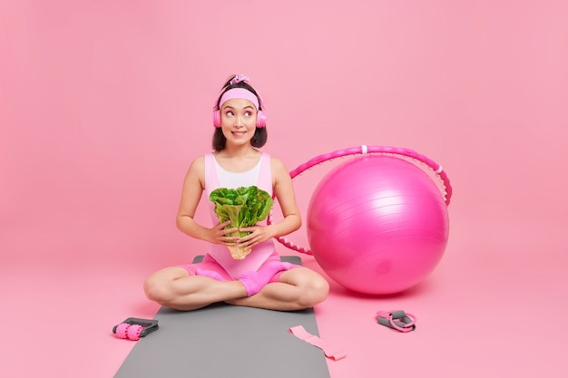 Une Femme Tient Une Salade Verte Assise Les Jambes Croisées Sur Un Karemat Continue De Suivre Un Régime Mène Un Mode De Vie Sain A Des Accessoires De Sport