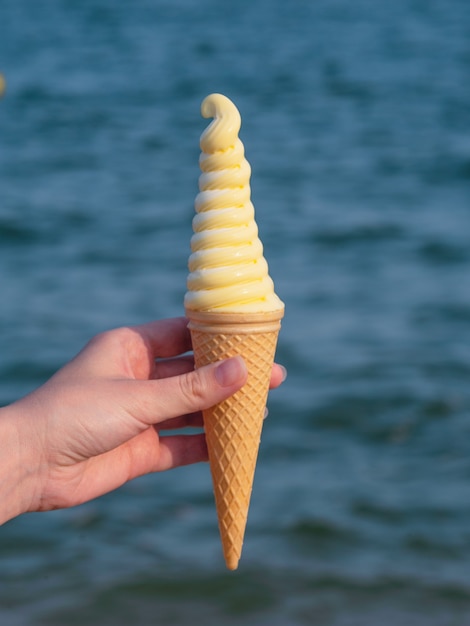 Une femme tient une savoureuse glace sur la plage.