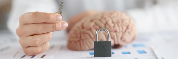 Une femme tient une serrure à clé et un cerveau humain sur le symbole du bureau comme clé de l'esprit de quelqu'un