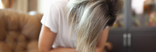 La femme tient son corps dans ses mains et souffre de la douleur tout en étant assise sur le canapé concept de