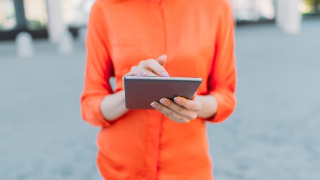 Une femme tient une tablette dans les mains et l'utilise.