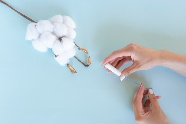 Une femme tient un tampon hygiénique blanc dans ses mains. Jours de menstruation. Concept d'hygiène et de soins du corps