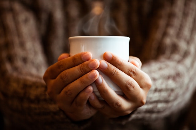 Femme tient une tasse de café dans un café au jour de pluie