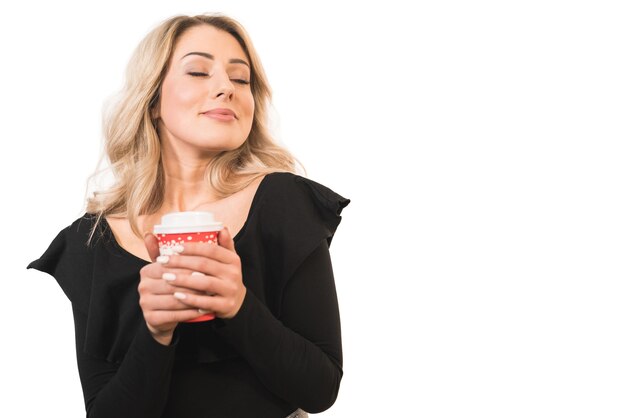 La femme tient la tasse de café sur le fond blanc