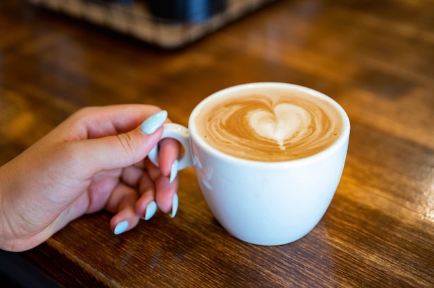 Femme tient une tasse de café avec de la mousse