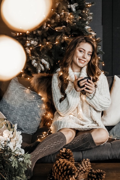 La femme tient une tasse de café et sourit.