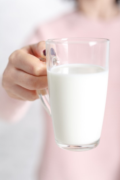 La femme tient une tasse de lait en verre