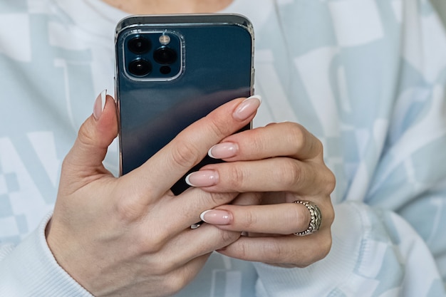 Femme tient un téléphone portable à la main et envoie des SMS