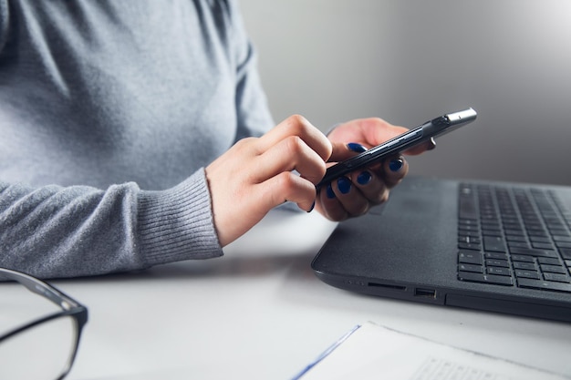 Une femme tient un téléphone portable et un ordinateur portable