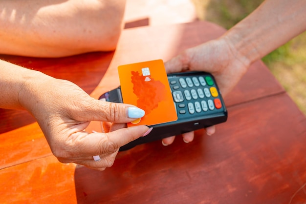 Photo une femme tient un terminal de paiement bancaire sans fil pour traiter l'acquisition d'une carte de crédit dans un magasin, un café et un restaurant