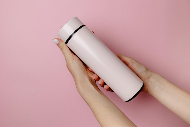 Une femme tient un thermos rose