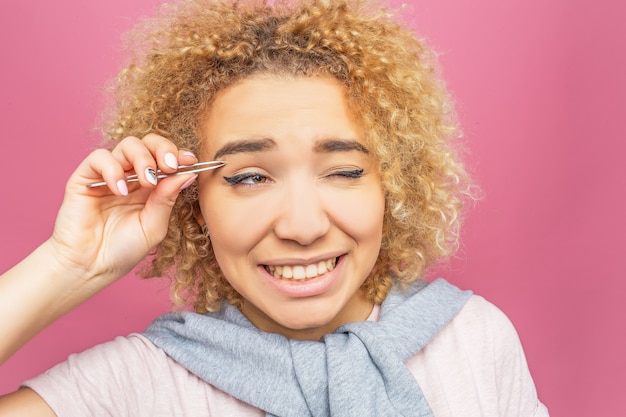 Une femme tire les cheveux de ses sourcils à l'aide d'une pince à épiler