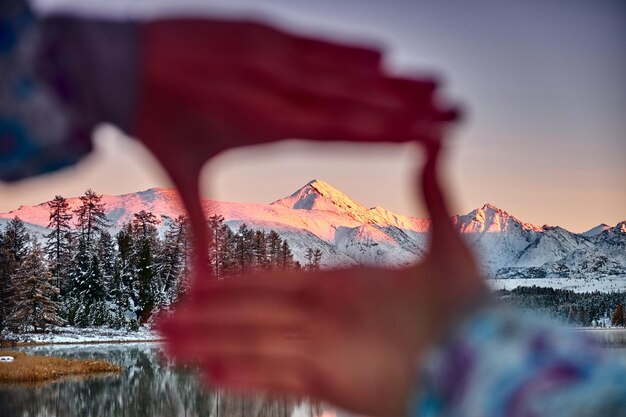 La femme tire ses mains vers la montagne, elle regarde à travers ses pouces