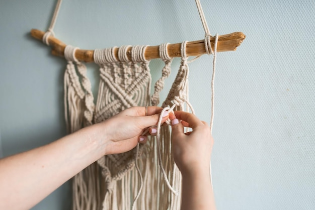 Une femme tisse une décoration intérieure à partir d'un processus de création de panneaux en macramé en fil de coton