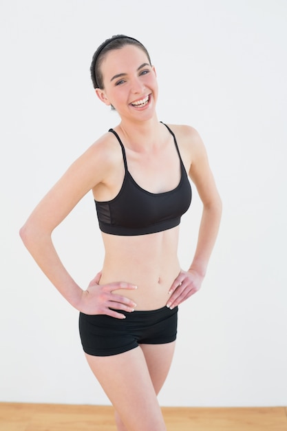 Femme tonique souriante avec les mains sur les hanches en studio de remise en forme