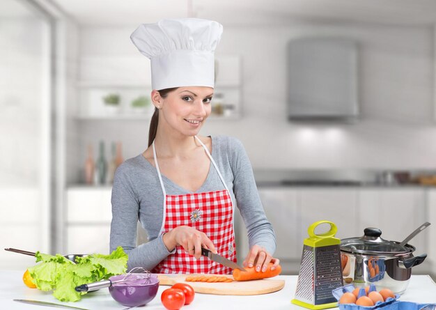 Femme en toque lisant un livre de cuisine et levant une cuillère