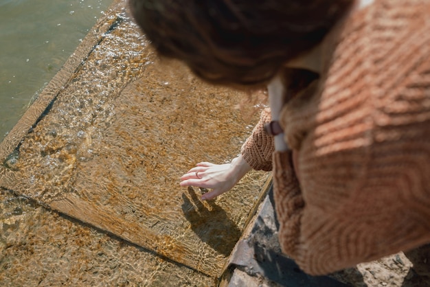 Femme touchant l'eau froide sur une jetée