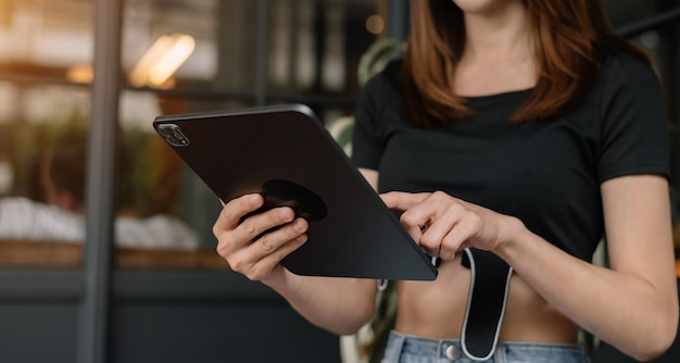 Femme touchant sur l'écran de la tablette en se tenant debout dans un arrière-plan de bureau flouxA