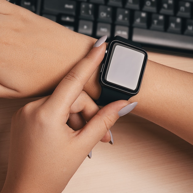 Femme touchant la main de la montre intelligente sur le bureau.