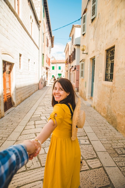 Femme de tourisme en robe d'été jaune marchant dans la petite rue de la ville croate