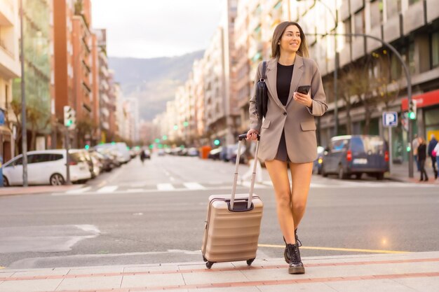 Femme de tourisme avec valise dans le style de vie de vacances de concept de ville en regardant le téléphone