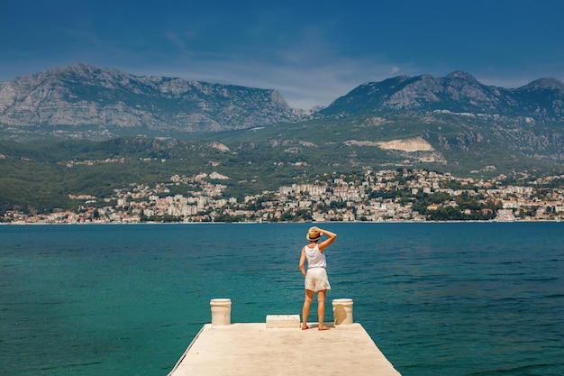 Femme touriste au chapeau de paille debout sur le bord d'une jetée