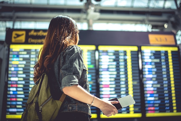 Femme touriste de beauté en regardant les horaires de vol pour vérifier le temps de décollage