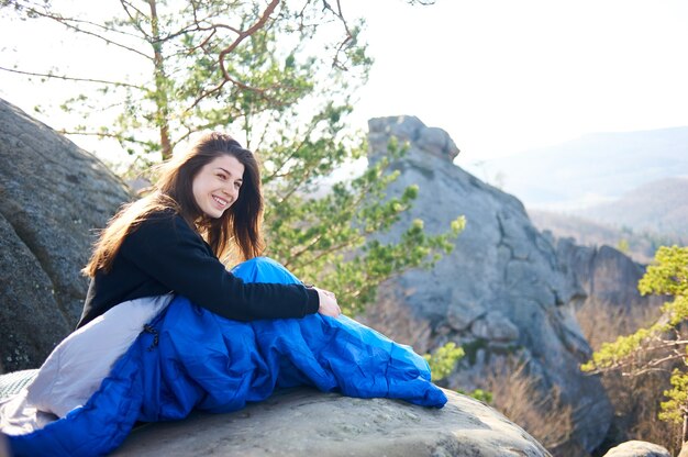 Femme de touriste dans des sacs de couchage sur de gros rochers