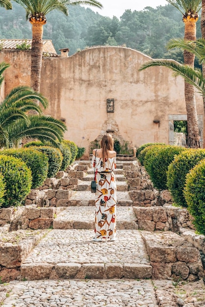 Femme touriste debout sur les marches au milieu de plantes dans un parc historique contre le ciel