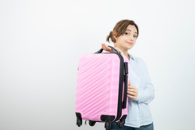 Photo femme touriste debout et tenant une valise de voyage rose. photo de haute qualité