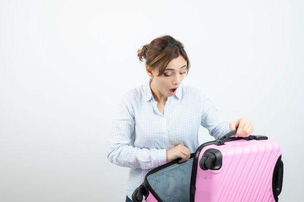Photo femme touriste debout et tenant une valise de voyage rose. photo de haute qualité