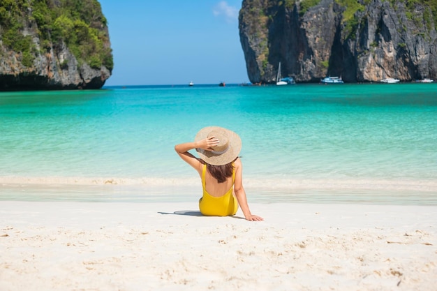 Femme touriste en maillot de bain jaune et chapeau heureux voyageur prenant un bain de soleil à la plage de Maya Bay sur l'île de Phi Phi Krabi Thaïlande destination historique Asie du Sud-Est Voyage vacances et concept de vacances