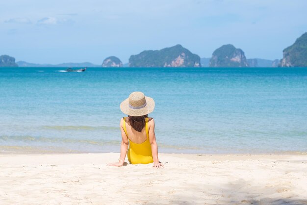 Femme touriste en maillot de bain jaune et chapeau heureux voyageur prenant un bain de soleil sur la plage paradisiaque sur les îles destination wanderlust Asie Voyage vacances d'été tropicales et concept de vacances