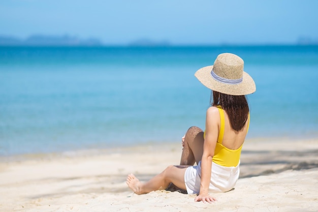 Femme touriste en maillot de bain jaune et chapeau heureux voyageur prenant un bain de soleil sur la plage paradisiaque sur les îles destination wanderlust Asie Voyage vacances d'été tropicales et concept de vacances