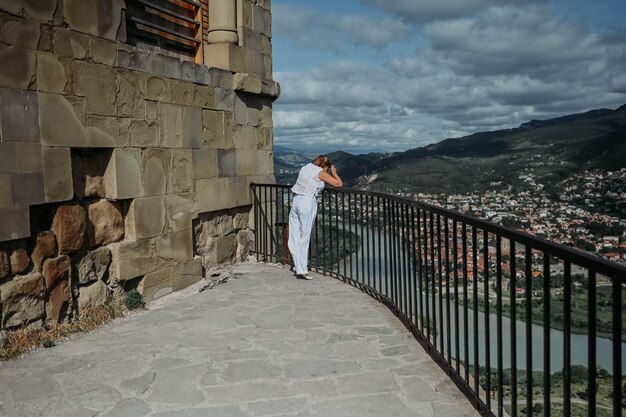 Photo une femme touriste mature se promène sur la terrasse d'observation des ruines d'un ancien monastère près de la ville de mtskheta, en géorgie.