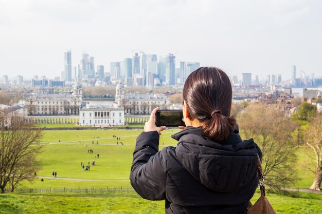 Femme touriste prenant des photos dans le parc avec ville bulding