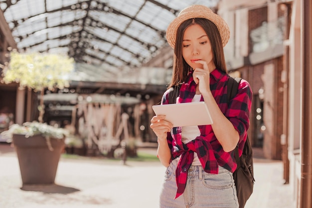 Femme touriste réfléchie regardant dans une tablette numérique à l'extérieur