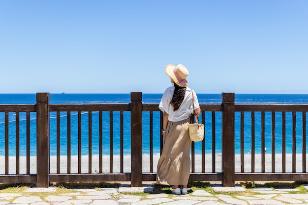 Une femme touriste regarde la plage.