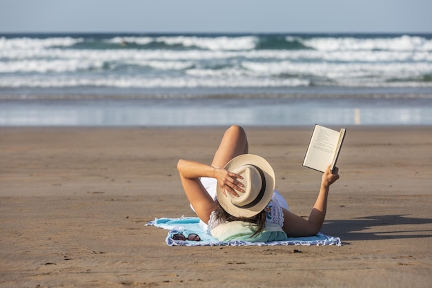 Femme touriste relaxante sur la plage avec un livre