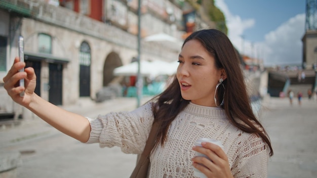 Une femme touriste se fait un selfie avec du café en vue de la ville en gros plan. Une brune pose.