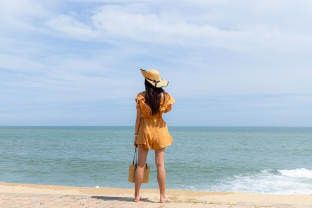 Une femme touriste se tient sur la plage.