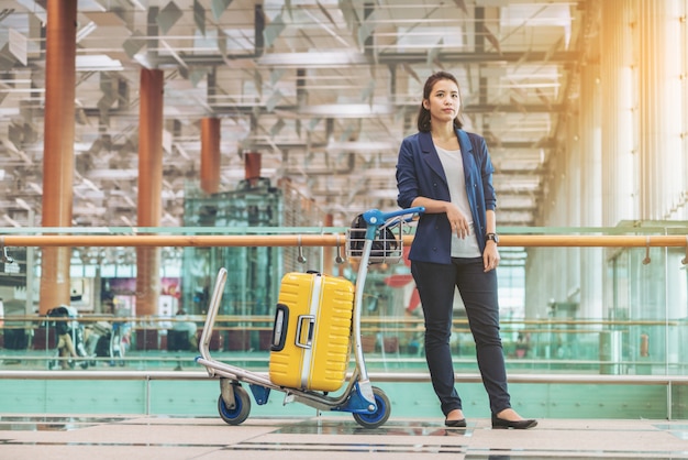 Femme touristique dans le terminal de l'aéroport avec des bagages