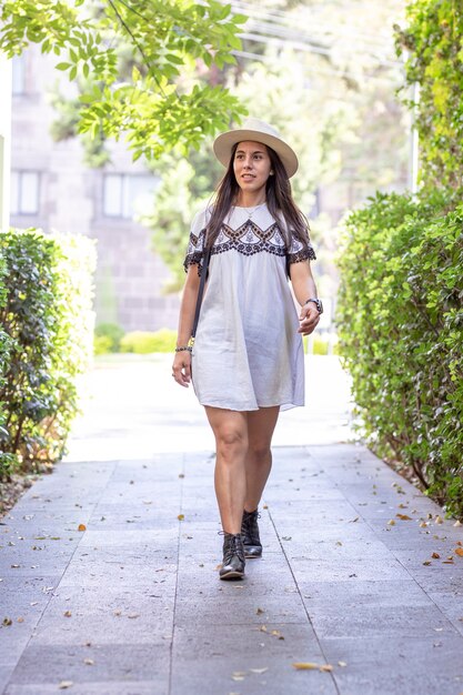 Femme touristique latina marchant dans une rue avec des arbres sur les côtés