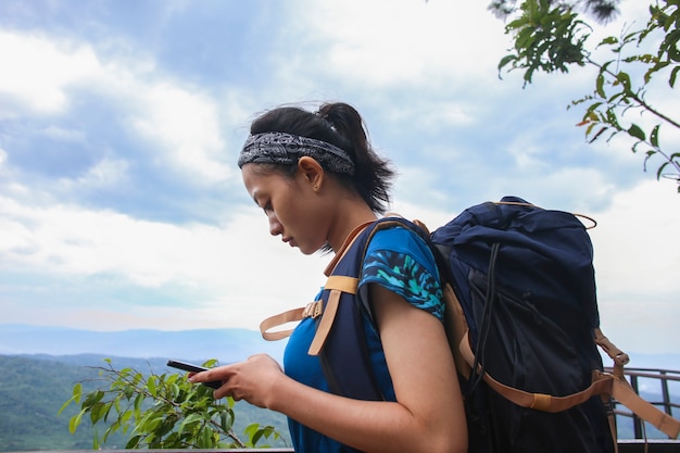 Une femme touristique utilise un smartphone dans les montagnes